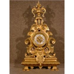 Une pendule de style Louis XIV en bronze doré surmontée d'une urne fleurie....