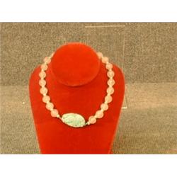 Un collier formé de boules de quartz rose et de perles de jade supportant un médaillon de jade sc...