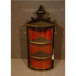 Une vitrine suspendue en bois noirci souligné de motifs dorés, la porte munie d'un panneau vitré...