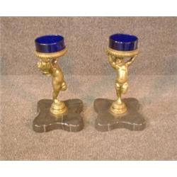 Une paire de salières en verre bleu supportées par 2 chérubins en bronze sur une base en marbre....