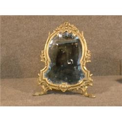 Un miroir de table de style Louis XVI en bronze à décor de rubans et de fleurs....