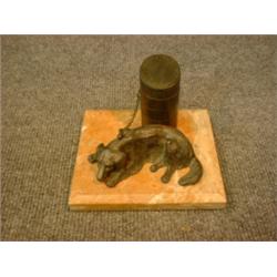 Un encrier en bronze patiné en forme de chien étendu enchaîné à un pilier....