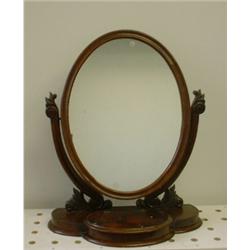 Un miroir à raser victorien en acajou, le miroir ovale sur des supports à décor de feuilles repos...