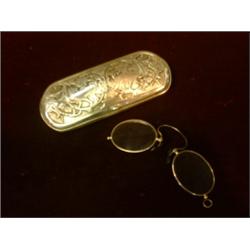 Un pince-nez dans un étui américain en argent à décor de loups dans des feuillages....