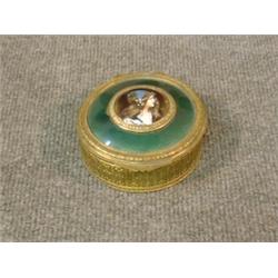 Une boîte en métal doré, le couvercle orné d'un médaillon en émail décoré d'un profil de jeune fi...