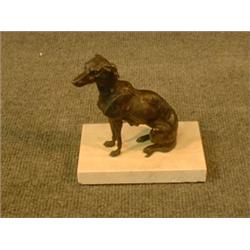 Un sujet en bronze patiné représentant un lévrier assis.  A patinated bronze figure of a seated g...