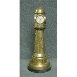 Une pendule en métal argenté et doré en forme de phare, la partie supérieure tournante munie d'un...