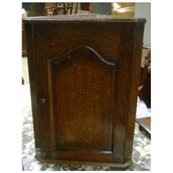 Un cabinet d'angle en chêne, la porte ornée d'un panneau chantourné....
