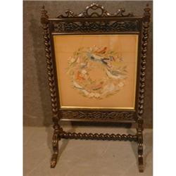 Un écran de cheminée victorien en bois noirci renfermant une tapisserie au petit point ornée d'oi...