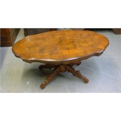 Une table à café ovale en noyer, le plateau chantourné sur une colonne reposant sur quatre pieds...