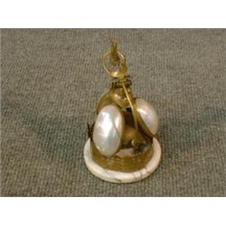 Une sonnette de table en nacre à monture de laiton.  A mother of pearl table bell with brass moun...