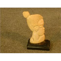 Un sujet africain en ivoire sculpté représentant un buste féminin....