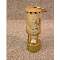Une lampe de mineur en laiton et métal.  A brass and metal miner's lamp. $100/150...