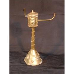 Une lampe à huile en laiton à décor de masques.  A brass oil lamp decorated with masks. $150/250...