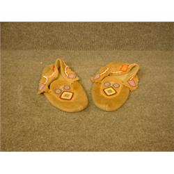 Une paire de mocassins indiens en peau à décor perlé polychrome....