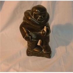 Une sculpture inuit en stéatite en forme de chasseur brandissant un couteau en ivoire....