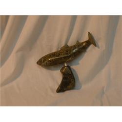 Une sculpture inuit en stéatite représentant un poisson sur un support....