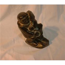 Une sculpture inuit en stéatite représentant un chasseur rapportant un phoque....