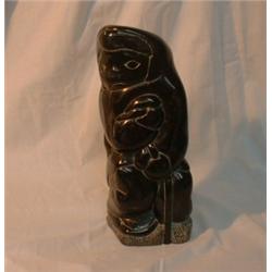 Une sculpture inuit en stéatite représentant un homme à genoux, signée....