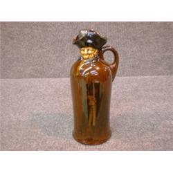 Une bouteille en porcelaine Kingsware de Royal Doulton à décor moulé d'un veilleur, le corps pein...