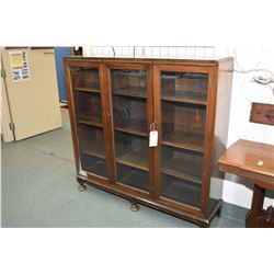 Mid 20th century mahogany three door book cabinet on turned bun supports, 54" wide