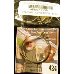 (2) coin bezels, a used half dollar bezel and a new quarter bezel in the original packaging from APM