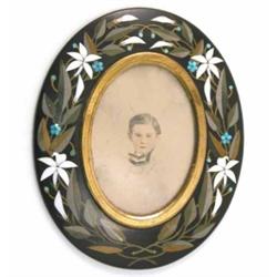 A Derbyshire black marble and stone inlay oval frame, decorated border of white lilies and laurel...