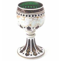 A 19th century Bohemian green glass goblet, overlaid in white and gilded with vine leaves, on spr...
