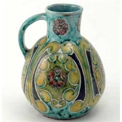 A Della Robbia jug, 1894-1901, painted with stylised flowers and scrolls against a mottled green...