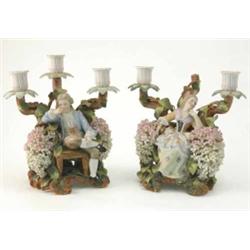 A pair of Thuringian candelabra figures, male and female seated amidst foliage, sconces on branch...