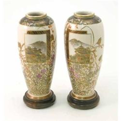 A pair of Satsuma vases, Meiji period, each painted with a landscape panel and wild flowers, on s...