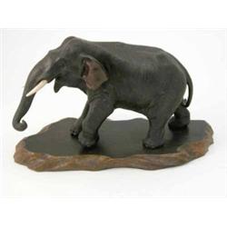 A Japanese bronze model of an elephant, with ivory tusks, 14ins, on hardwood stand...