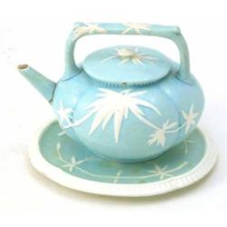 A Wedgwood majolica teapot, on stand, oval shape moulded with white palms against a sky-blue grou...