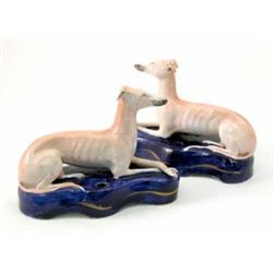 A pair of Victorian greyhound inkwells, each recumbent on blue-glazed cushion base, 6.25in. long...