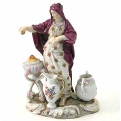 A 19th century Volkstedt figure of a lady, wearing full-length robe and warming herself beside br...