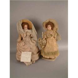 A wax over papier-mache lady doll, with inset glass eyes, Edwardian lace dress and bonnet, carryi...