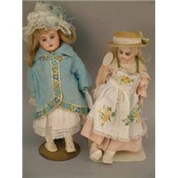 A German shoulder-bisque doll with fixed paperweight eyes, open mouth, pierced ears and clothed k...