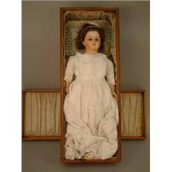 A 19th century composition doll, with fixed glass eyes and clothed mouth, dressed in christening...