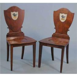 A pair of George III mahogany hall chairs, with shield backs painted with crests on square tapere...