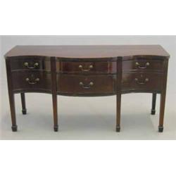 A late George III mahogany serpentine sideboard, with six drawers fitted brass loop handles on si...