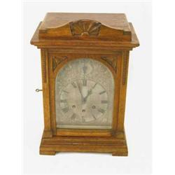 An Edwardian oak chiming mantel clock, with arched silvered dial and German movement, 17ins...