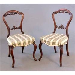 A set of four Victorian walnut dining chairs, with carved spoon shape backs on cabriole legs...