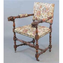 A late Victorian oak elbow chair, with upholstered back, seat and arm pads, carved lion's head ar...