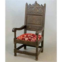 A 17th century oak high back elbow chair, with heavily carved decoration, bears date 1613, (repla...