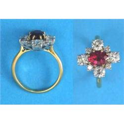 An 18ct gold cluster ring, claw-set with an oval synthetic ruby bordered by 8 brilliant cut diamo...