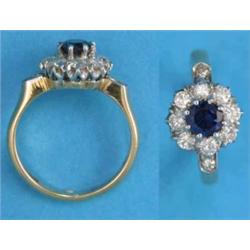 An 18ct gold, sapphire and diamond circular cluster ring, with diamond set shoulders...