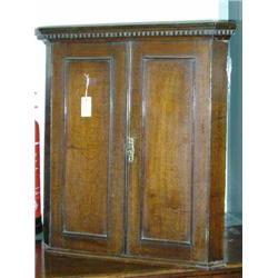 A George III oak hanging corner cupboard enclosed by panelled doors, H 83.5cms W 77cms...