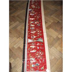 A Chinese red silk frieze panel worked with figures, 43cms x 203cms...