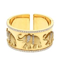 BRACELET: [1] 18 karat yellow and white gold hinged cuff style bangle bracelet with elephants and se