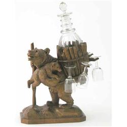 A Black Forest carved bear liqueur set, modelled holding a staff carrying a young bear and basket...